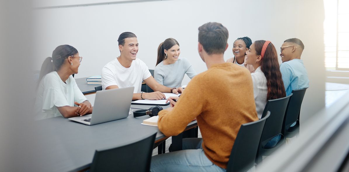 Een groep mensen zit lachend rond een tafel tijdens een gezellige bijeenkomst.