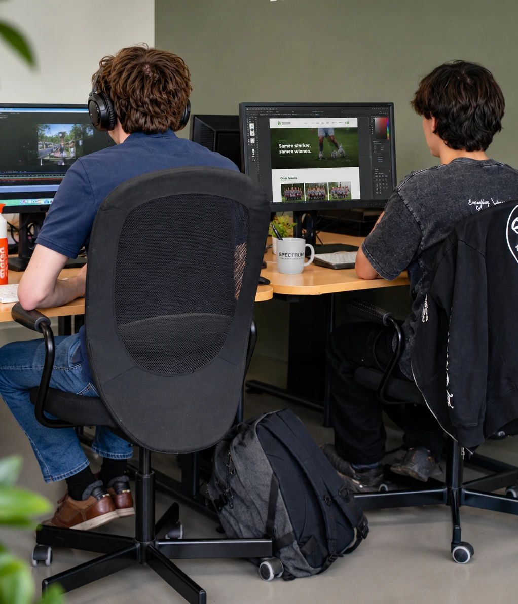 Twee mediënten werken achter beeldschermen aan video- en webprojecten.