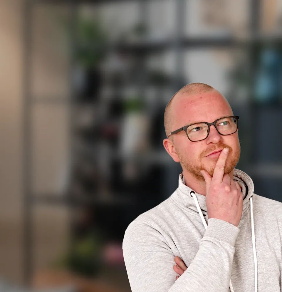 Man met bril en baard kijkt nadenkend met hand tegen zijn kin.