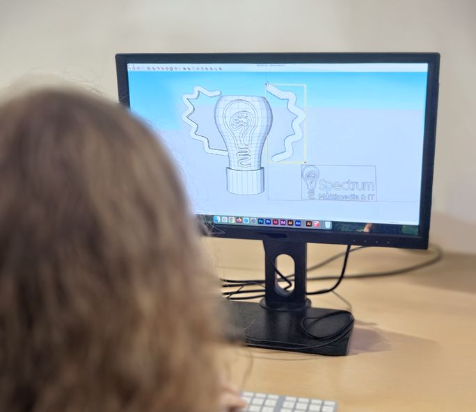 Deelneemster bekijkt een ontwerp op haar computerscherm, van achteren gefotografeerd.