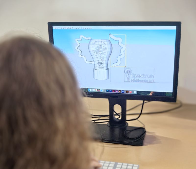 Deelneemster bekijkt een ontwerp op haar computerscherm, van achteren gefotografeerd.