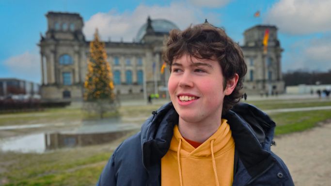 Glimlachende man met kort bruin haar poseert voor de camera.