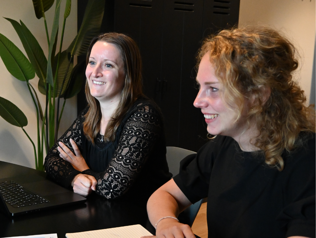 Twee collega's overleggen samen achter een computer.