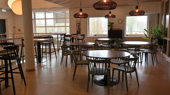 Gezellige kantine met tafels, stoelen en warme verlichting.
